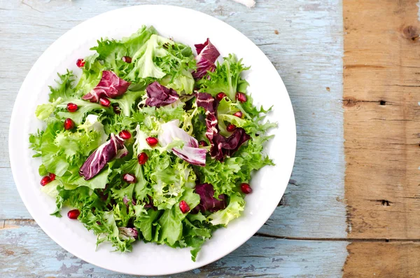 Salada verde com espinafre, frisee, arugula, radicchio e sementes de romã em fundo de madeira azul — Fotografia de Stock