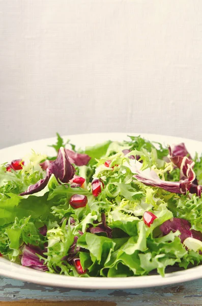 Salada verde com espinafre, frisee, arugula, radicchio e sementes de romã em fundo de madeira azul — Fotografia de Stock