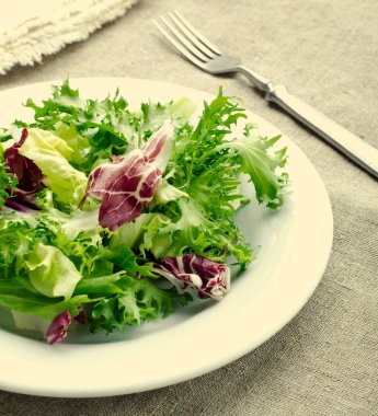 Ispanak, frisee, roka, radicchio, beyaz peynir ve mavi ahşap arka plan üzerinde siyah susam ile yeşil salata