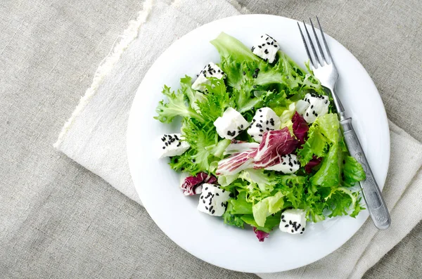 Insalata verde con spinaci, frisee, rucola, radicchio, formaggio feta e semi di sesamo nero su fondo di legno blu — Foto Stock