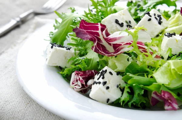 Salada verde com espinafre, frisee, arugula, radicchio, queijo feta e semente de gergelim preto em fundo de madeira azul — Fotografia de Stock