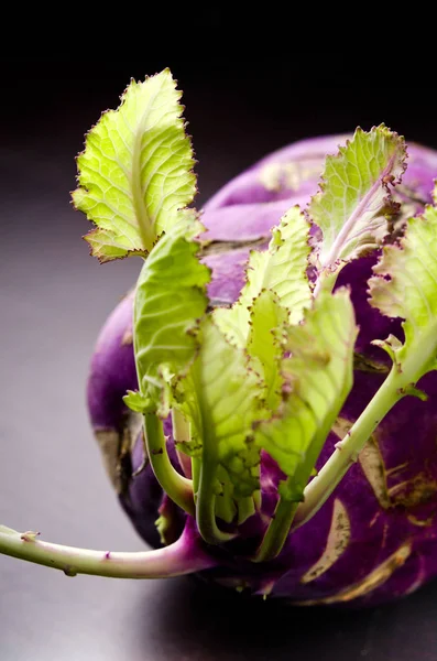 Repolho kohlrabi roxo com folhas verdes na mesa de madeira escura — Fotografia de Stock