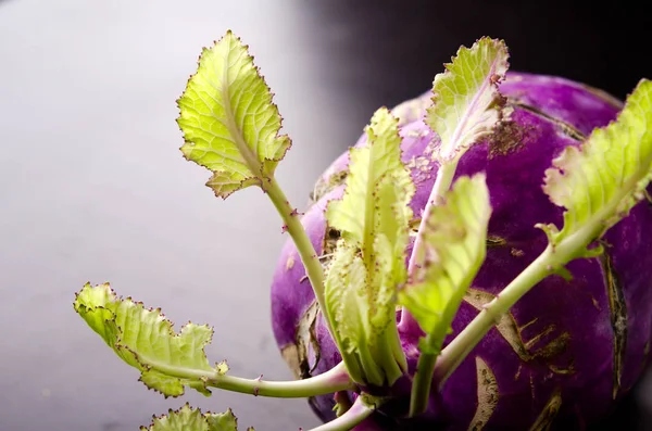 Repolho kohlrabi roxo com folhas verdes na mesa de madeira escura — Fotografia de Stock