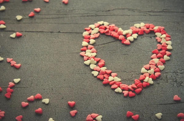 Corazón hecho con pequeños corazones de caramelo, rosa, rojo, colores whie, sobre fondo oscuro. Amor, concepto de San Valentín. Vista superior, espacio de copia . — Foto de Stock