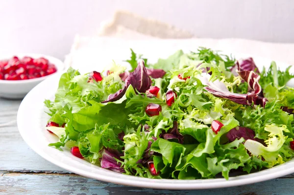 Salada verde com espinafre, frisee, arugula, radicchio e sementes de romã em fundo de madeira azul — Fotografia de Stock