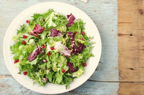 Zöld saláta, spenót, Frisée, radicchio, sült saláta kitûnõ és gránátalma magokat a kék fa háttér — Stock Fotó