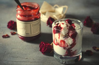 Dondurma dondurma çikolatalı topping ve koyu arka plan üzerinde kurutulmuş gül çiçekleri kiraz. Aşk, Sevgililer günü kavramı. Kopya alanı