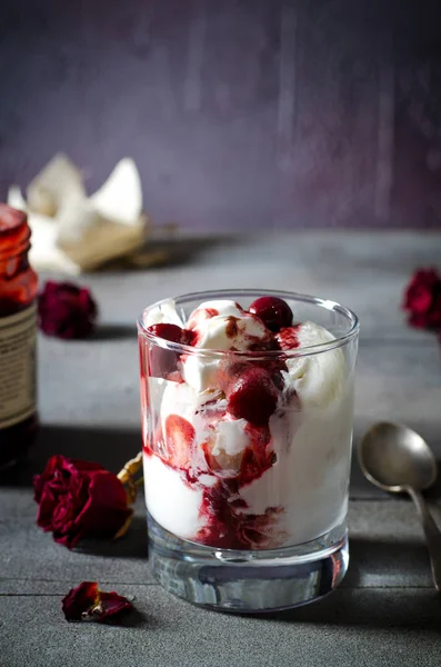 Dondurma dondurma çikolatalı topping ve koyu arka plan üzerinde kurutulmuş gül çiçekleri kiraz. Aşk, Sevgililer günü kavramı. Kopya alanı