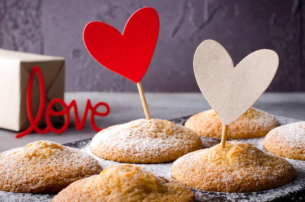 Muffin dolci su sfondo scuro con cuori di carta rossi e kraft, per San Valentino . — Foto Stock