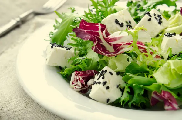 グリーン サラダほうれん草、ブラックラディッシュ、ルッコラ、トレビス、フェタチーズ、青い木製の背景に黒こまの種子 — ストック写真