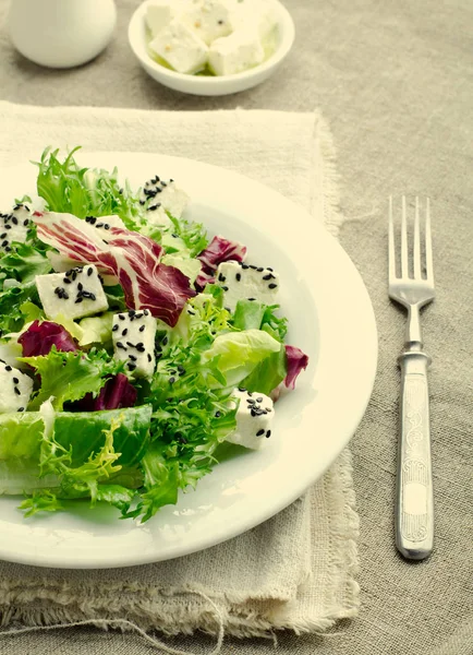 Insalata verde con spinaci, frisee, rucola, radicchio, formaggio feta e semi di sesamo nero su fondo di legno blu — Foto Stock