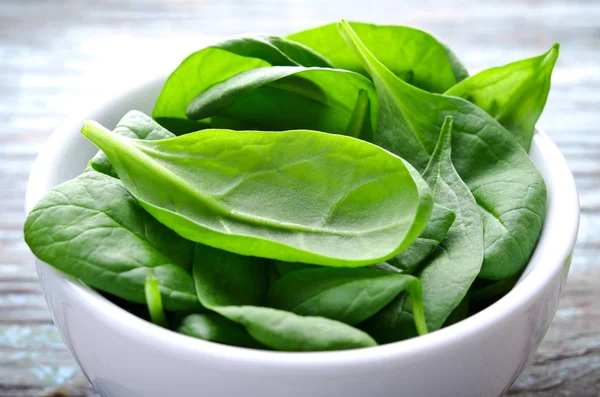 Fresh Baby spinach leaves in white bowl on blue wooden background. Top view with copy space, horizontal. Healthy, Ecology concept — Stock Photo, Image