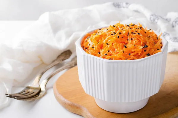 Salada de cenoura picante com sementes de gergelim preto em tigela branca no tabuleiro wooned . — Fotografia de Stock