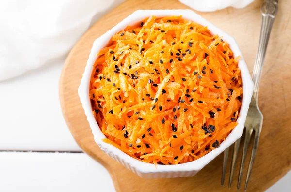 Salada de cenoura picante com sementes de gergelim preto em tigela branca no tabuleiro wooned . — Fotografia de Stock