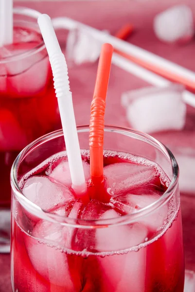 冷樱桃饮料冰块与鸡尾酒管的眼镜，在粉红色的背景上 — 图库照片