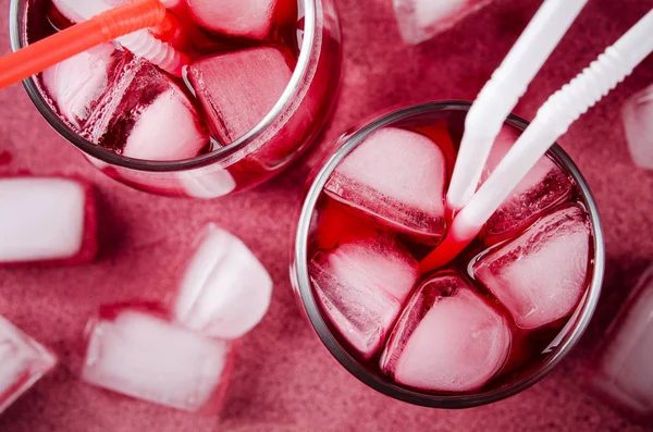 Cold cherry drink with ice cubes and cocktail tubes in glasses, on pink background — Stock Photo, Image