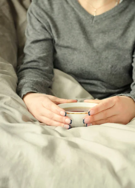 Frauenhände halten eine Tasse heißen Tee auf einer warmen Decke. — Stockfoto