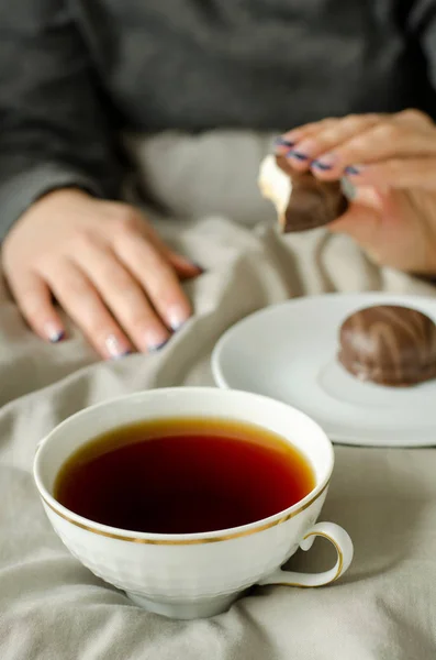 Manos femeninas sosteniendo una taza de té caliente en una manta caliente . —  Fotos de Stock