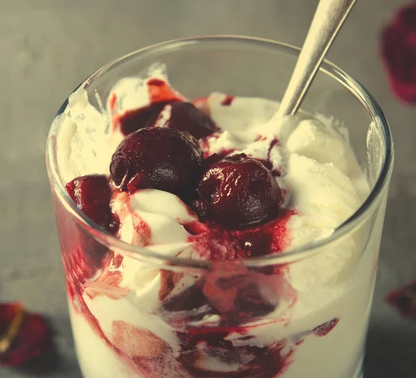 Gelato Sundae con ciliegia in topping cioccolato, e fiori di rosa secchi su sfondo scuro. Amore, concetto di San Valentino — Foto Stock