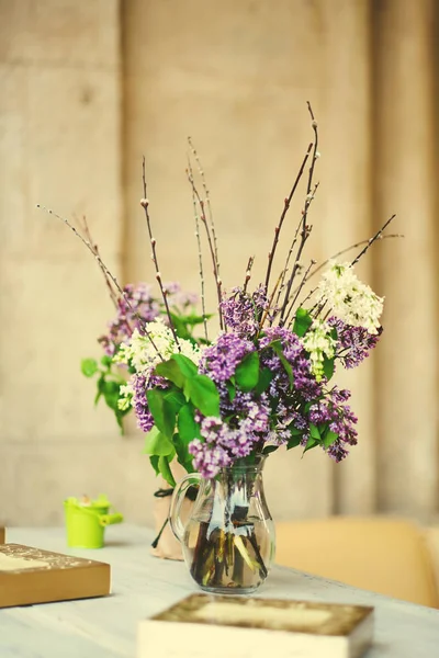 Rama con flores frescas de primavera lila en jarrón, en la mesa en el café — Foto de Stock