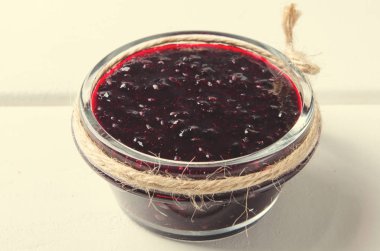 Beyaz ahşap zemin üzerinde blackcurrant reçel kavanoz.