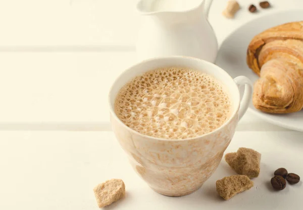 Traditionelles Frühstück mit frischen Croissants und Kaffee auf weißem Holzhintergrund. — Stockfoto