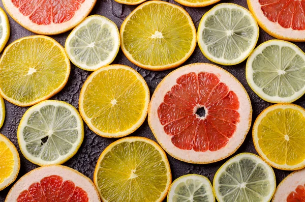 Fatias de frutas cítricas de limão, laranja, toranja no fundo escuro . — Fotografia de Stock