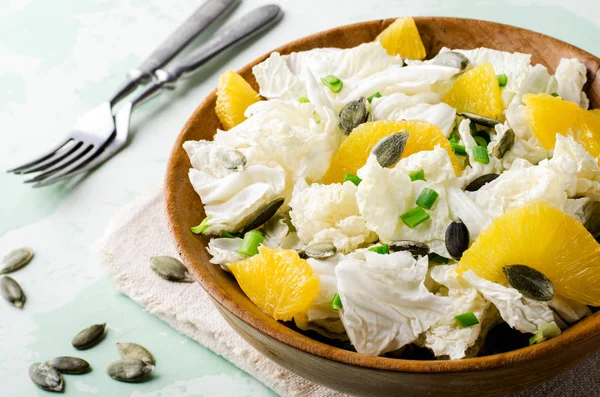 Ensalada de col china con semillas de naranja y calabaza en un tazón de madera —  Fotos de Stock