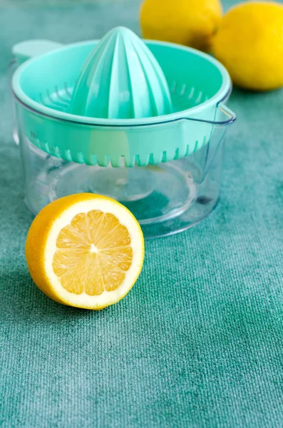 Fresh lemons with citrus squeezer on turquoise background. Copy space