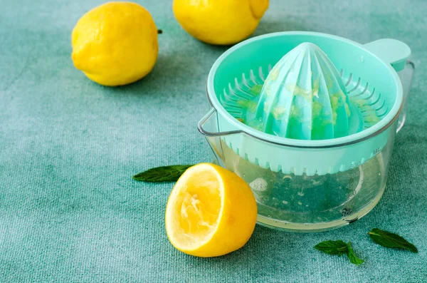 Limones frescos y menta con exprimidor de cítricos sobre fondo turquesa. Copiar espacio — Foto de Stock
