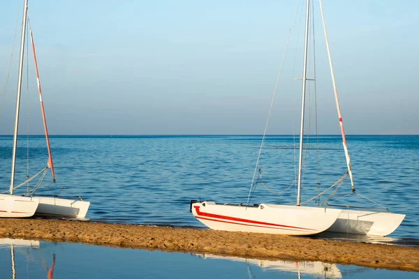 Біла вітрильна яхта на пляжі на спокійному морі . — стокове фото