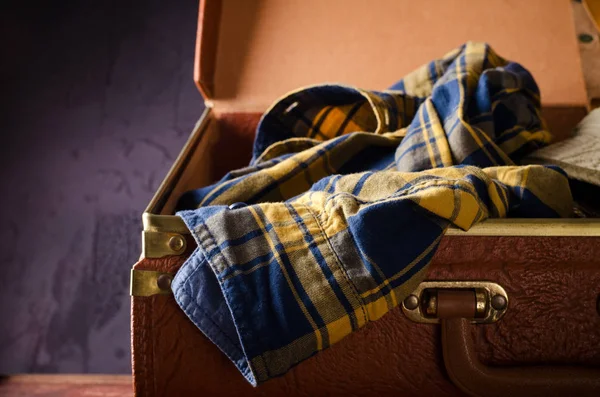 Velho vintage, retro mala aberta com mans camisa xadrez no fundo escuro. Conceito de viagem — Fotografia de Stock