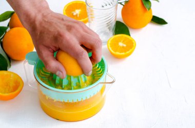 Taze sıkılmış portakal suyu mens elle, beyaz arka plan üzerinde turkuaz meyve sıkacağı