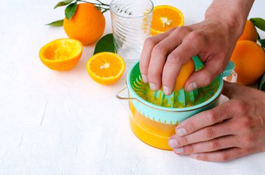 Taze sıkılmış portakal suyu mens ellerimden, beyaz arka plan üzerinde turkuaz meyve sıkacağı