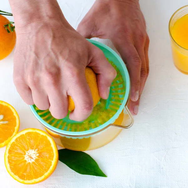 Taze sıkılmış portakal suyu mens ellerimden, beyaz arka plan üzerinde turkuaz meyve sıkacağı