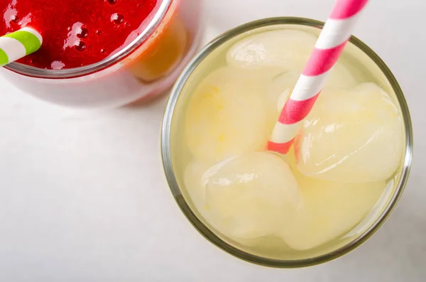 Smoothies aux fraises et limonade glacée avec tubes à cocktail dans des verres, sur fond blanc . — Photo