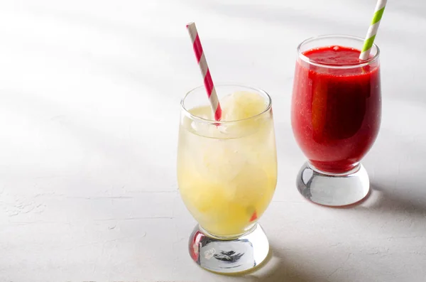 Strawberry smoothies and ice lemonade with cocktail tubes in glasses, on white background. — Stock Photo, Image