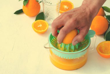 Taze sıkılmış portakal suyu mens elle, beyaz arka plan üzerinde turkuaz meyve sıkacağı