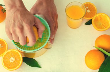 Taze sıkılmış portakal suyu mens ellerimden, beyaz arka plan üzerinde turkuaz meyve sıkacağı