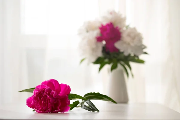 Peonías blancas y rosadas en jarrón sobre mesa blanca — Foto de Stock