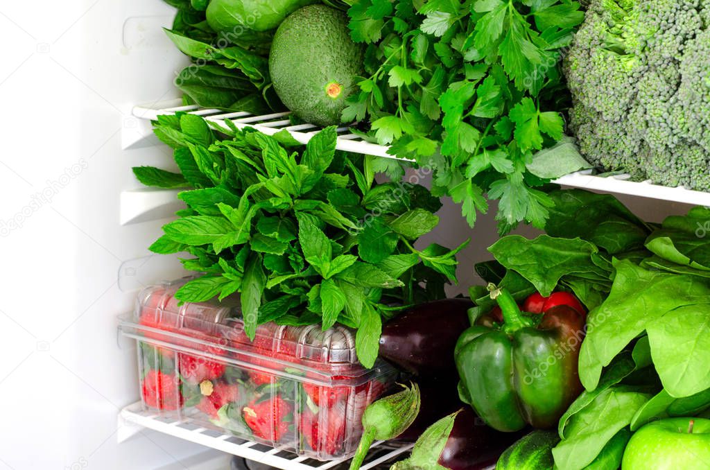 Greens, fruits and vegetables in fridge. Vegan, raw, healthy lifestyle concept