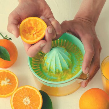 Taze sıkılmış portakal suyu mens ellerimden, beyaz arka plan üzerinde turkuaz meyve sıkacağı