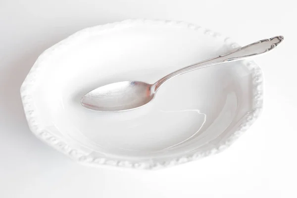 Leerer Teller mit Silberlöffel isoliert auf weiß — Stockfoto