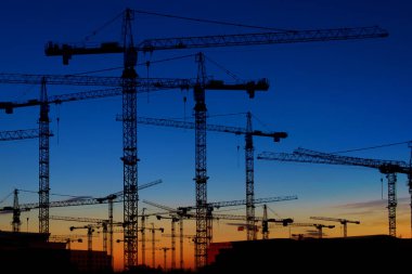 günbatımı gökyüzü - vinç siluet manzarası üzerinde birçok İnşaat vinçleri