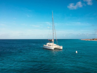 Sahildeki okyanusta beyaz yelkenli katamaran.  -