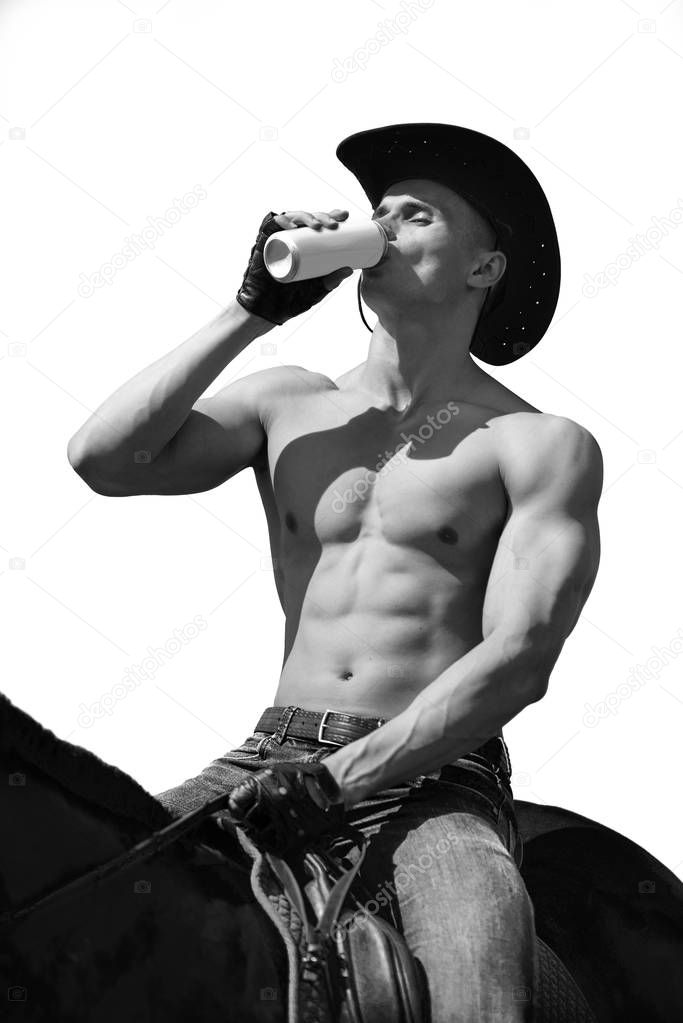 Macho man handsome cowboy on a horse drinking beer. Western style