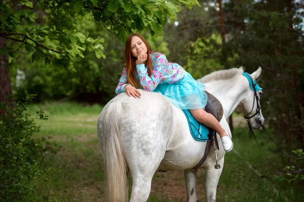 Rödhårig flicka och vit häst i skogen — Stockfoto