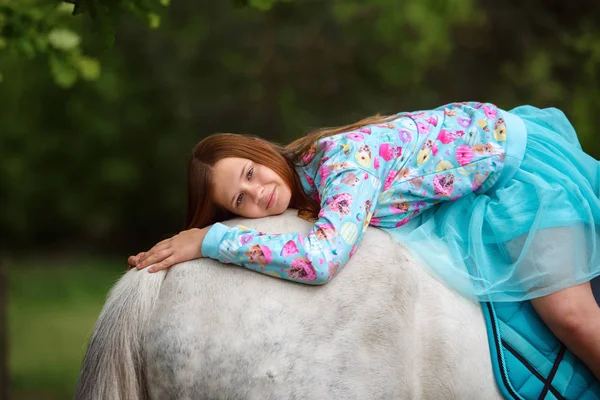 Рыжая девушка и белая лошадь в лесу — стоковое фото