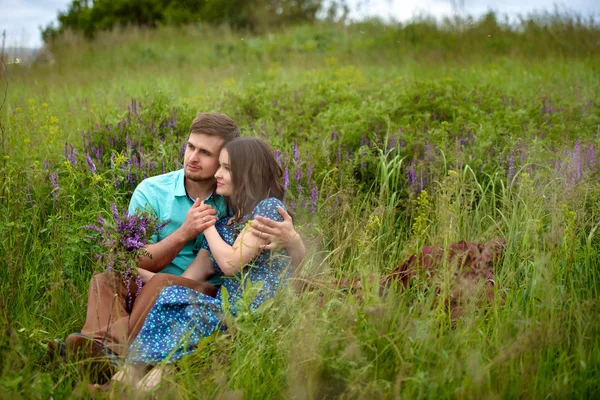 Milující pár seděli uprostřed květiny na louce. Líbánky — Stock fotografie