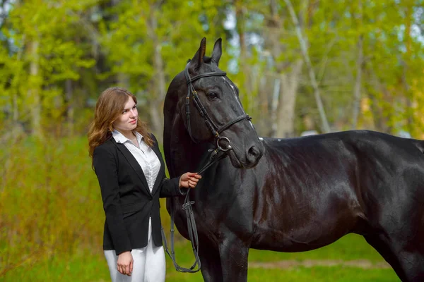 Νεαρό Κορίτσι Αναβάτη Ένα Μαύρο Άλογο Στην Υπαίθρια Σκηνή Άνοιξη — Φωτογραφία Αρχείου